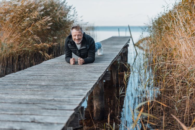 Mann 45+ trainiert auf Steg am Wasser