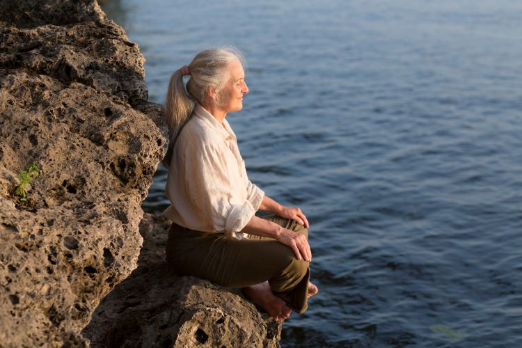 Frau 45+ meditiert am Meer